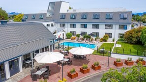 A hotel with a swimming pool, outdoor seating, and a view of mountains. - Scenic Hotel Marlborough (Blenheim)