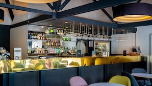 Un espace bar avec un assortiment de bouteilles d’alcool, de verres et une caisse enregistreuse.