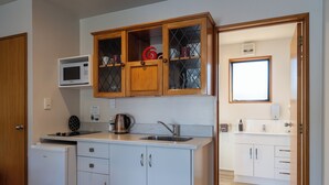 A compact kitchen with a microwave, kettle, and sink. - ASURE Highpark Motor Inn (Greymouth)