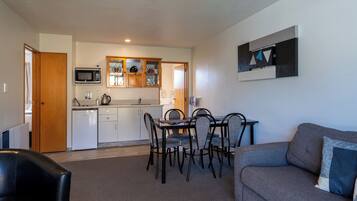Een ruimtelijk ingerichte woonruimte met een kitchenette, eethoek en een bank.