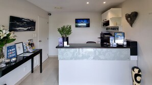 A reception area with a desk, a potted plant, a TV, and a heart-shaped decoration on the wall. - ASURE Highpark Motor Inn (Greymouth)