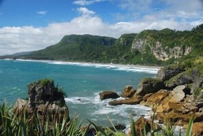 A coastal landscape with rocky terrain and a beach. - Fitzherbert Court Motel (Hokitika)