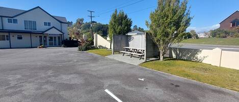 A reception area with a bench, a small shed, and a grassy area.
