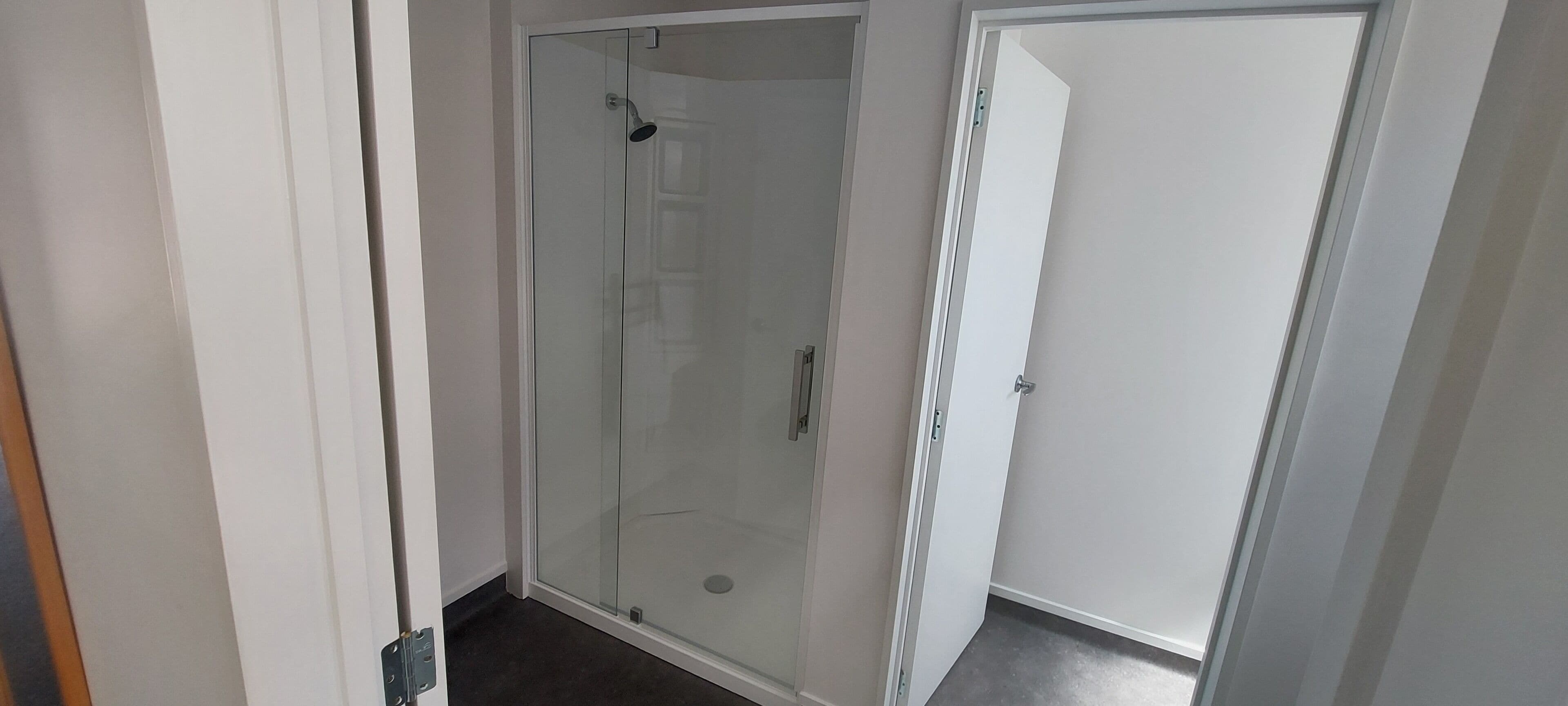 Un área de ducha con paredes de vidrio y una puerta que da a una habitación.