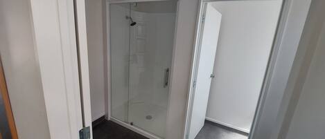 Un área de ducha con paredes de vidrio y una puerta que da a una habitación.