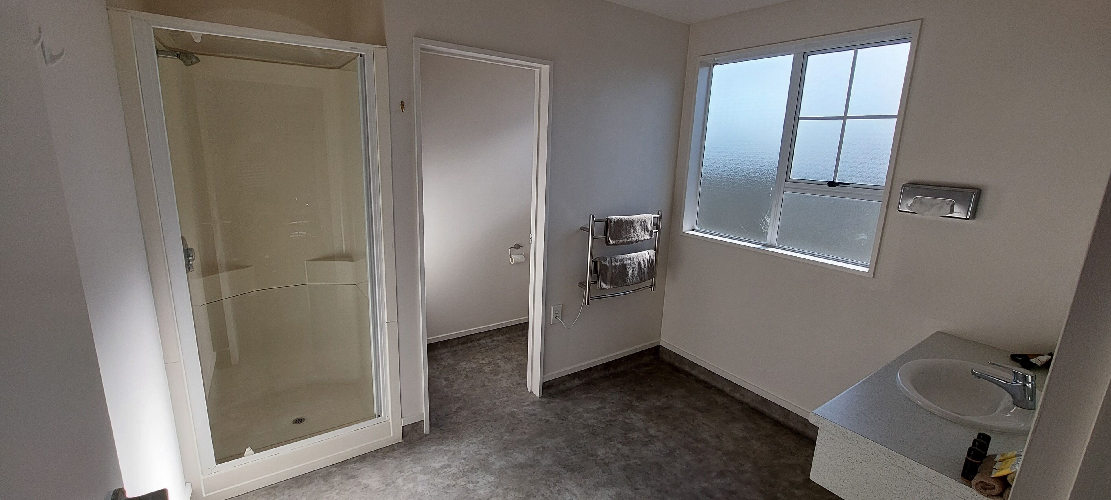 A bathroom with a shower, a toilet, a sink, and a window.