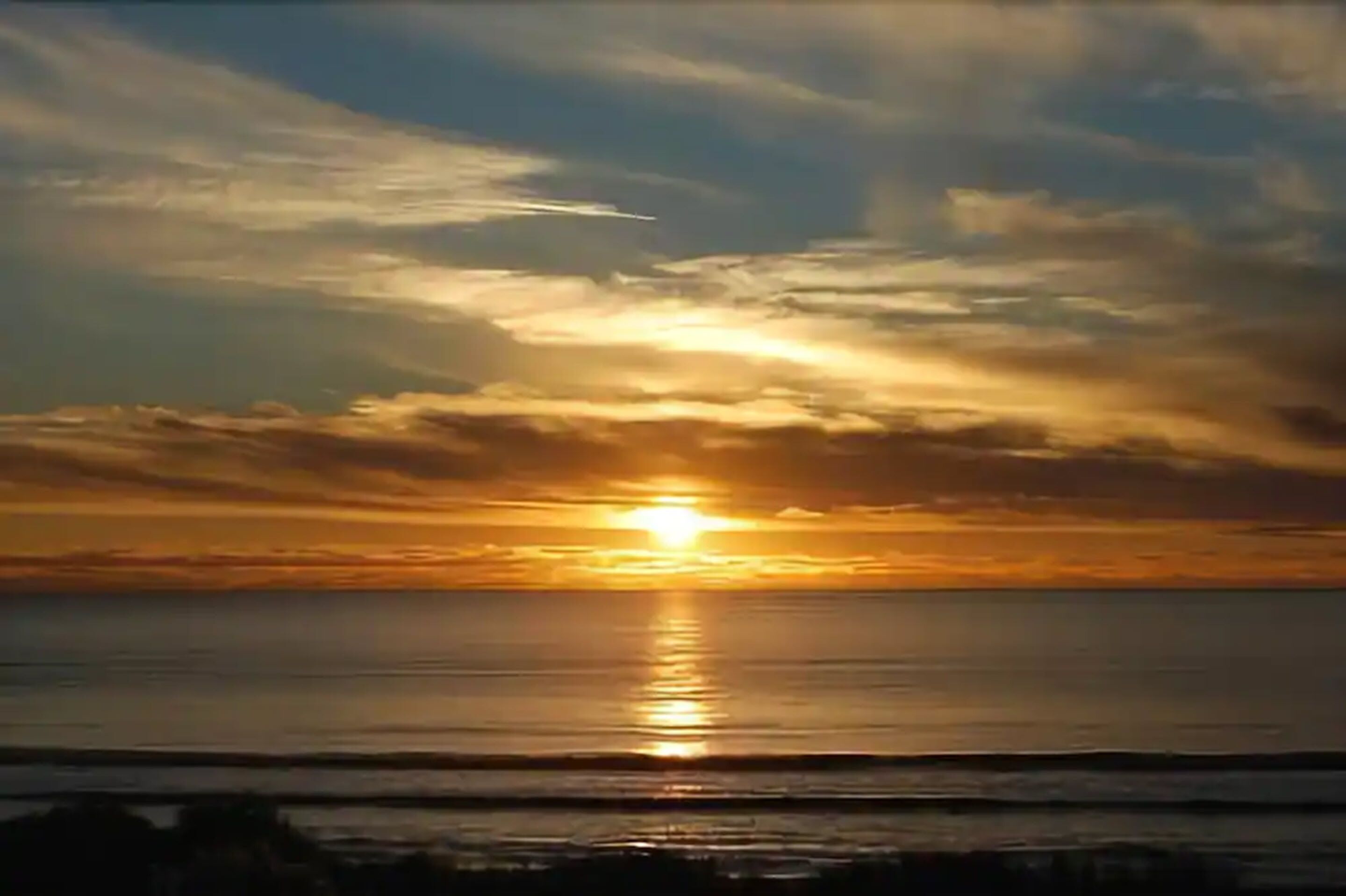 A sunset over a calm sea with a clear horizon.