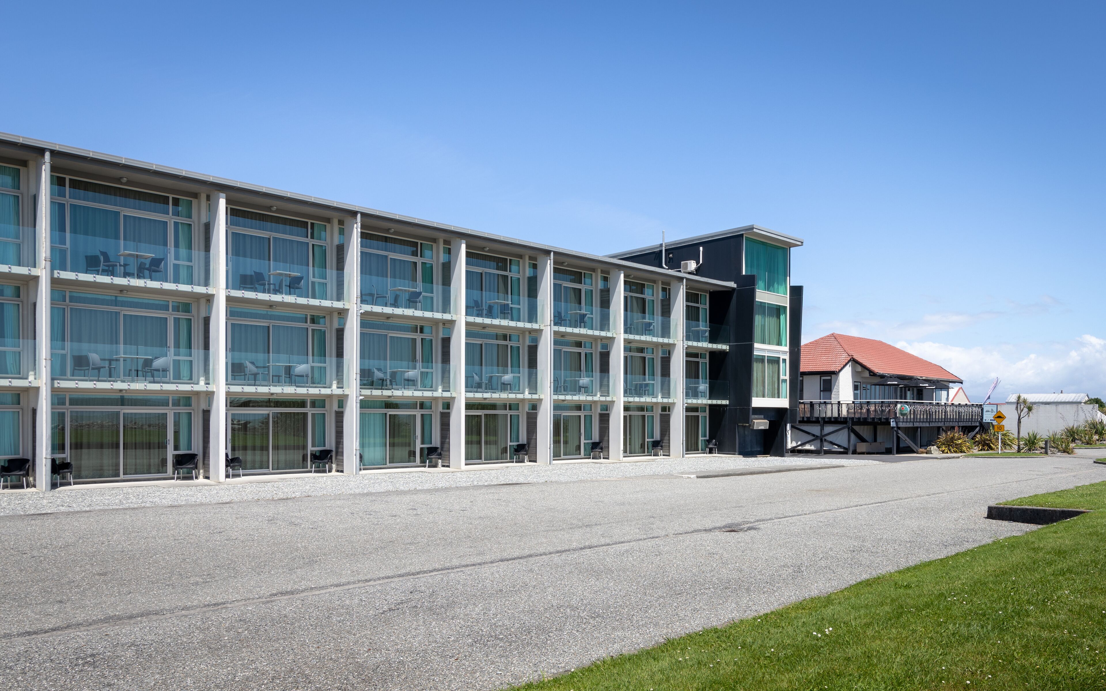 A modern hotel with multiple floors, large windows, and outdoor seating areas.