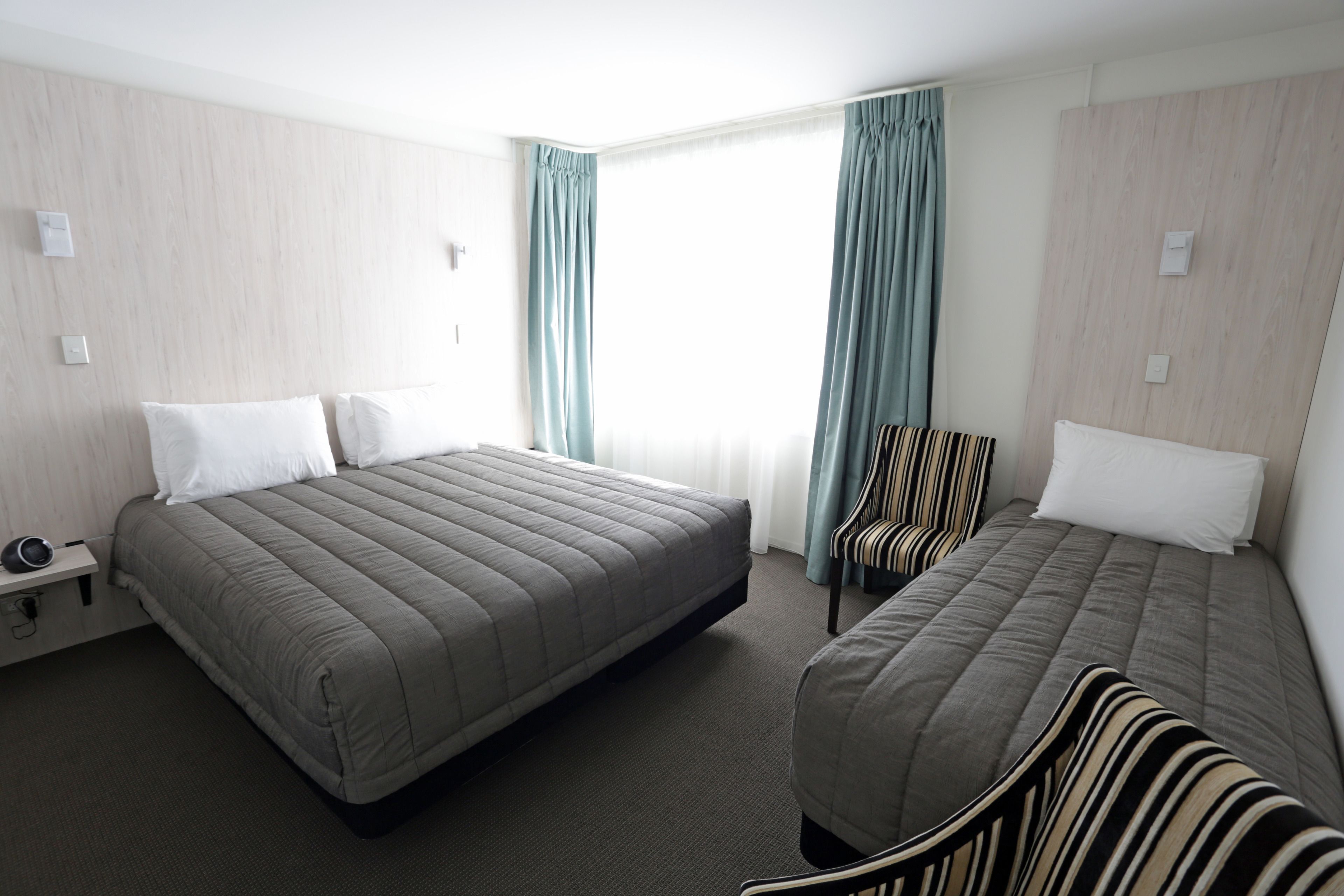 Ett hotellrum med två sängar, en stol och ett litet bord.