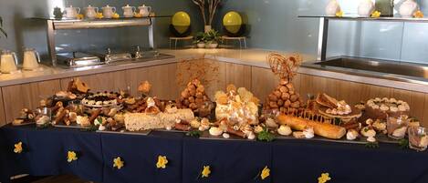 Uma mesa de buffet com diversos alimentos e um letreiro amarelo decorativo acima.