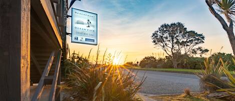 A beachfront property with a sign advertising ocean view rooms, a wooden structure, and surrounding vegetation.