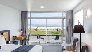 A hotel room with a large window offering a view of the beach and ocean. - Beachfront Hotel (Hokitika)