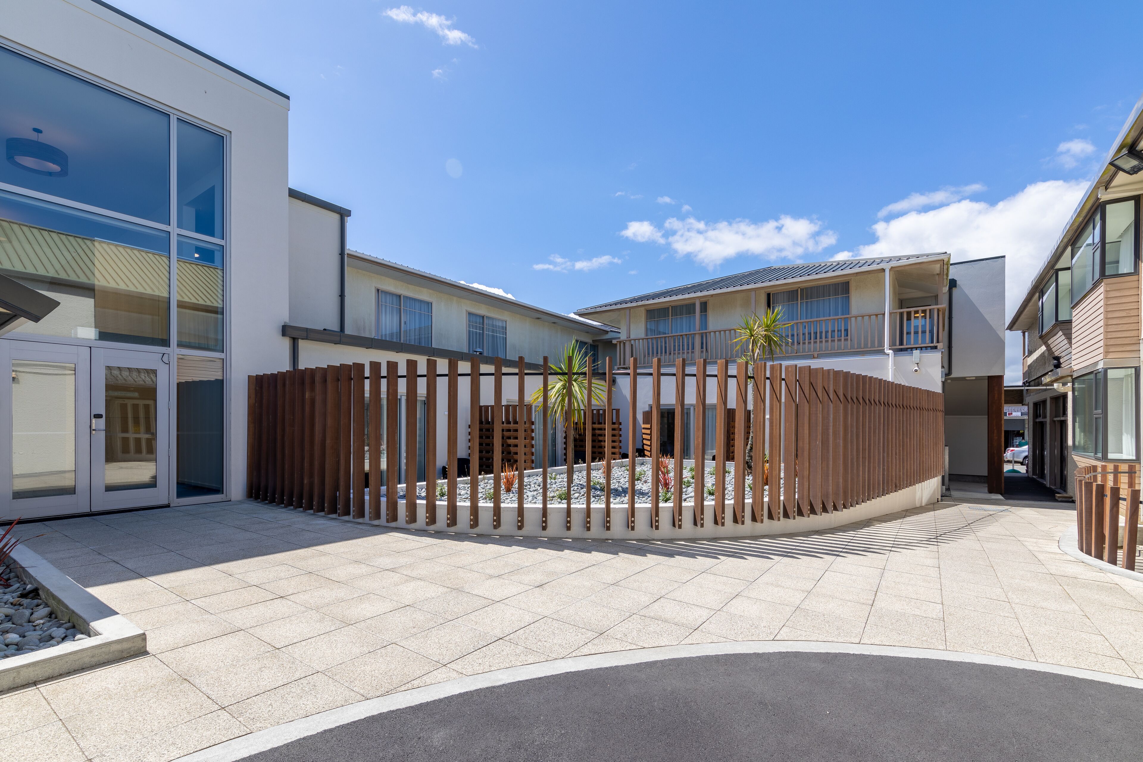 A modern building with a courtyard, large windows, and a wooden fence.