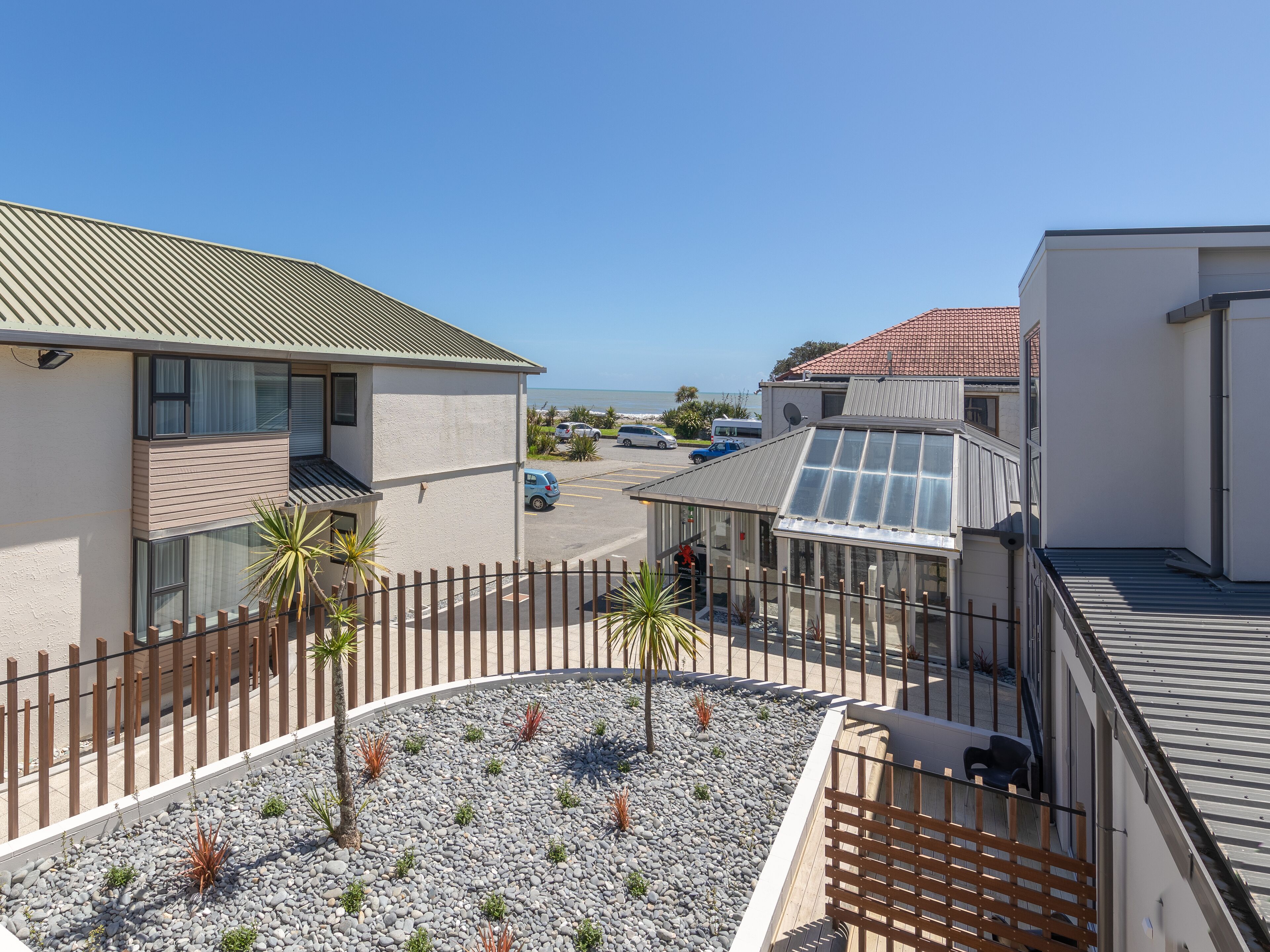 A modern building with a rooftop terrace, a parking area, and a view of the sea.