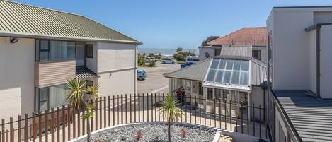 A modern building with a rooftop terrace, a parking area, and a view of the sea.