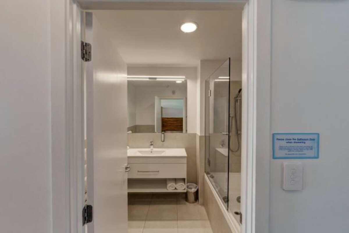 A modern bathroom with a glass shower enclosure, a white sink, and a mirror above the vanity.