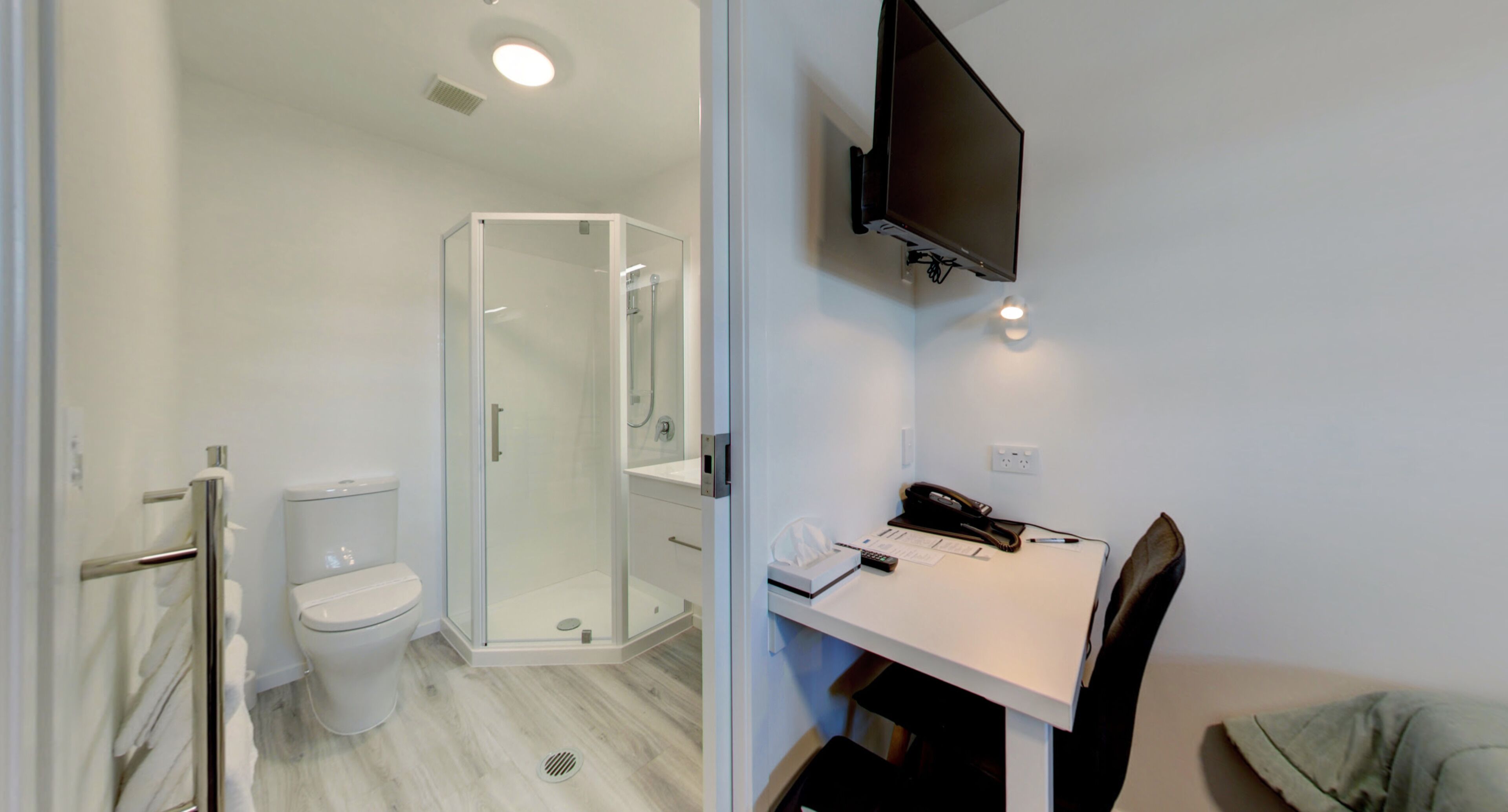 A modern bathroom with a toilet, shower, and glass-enclosed shower area.