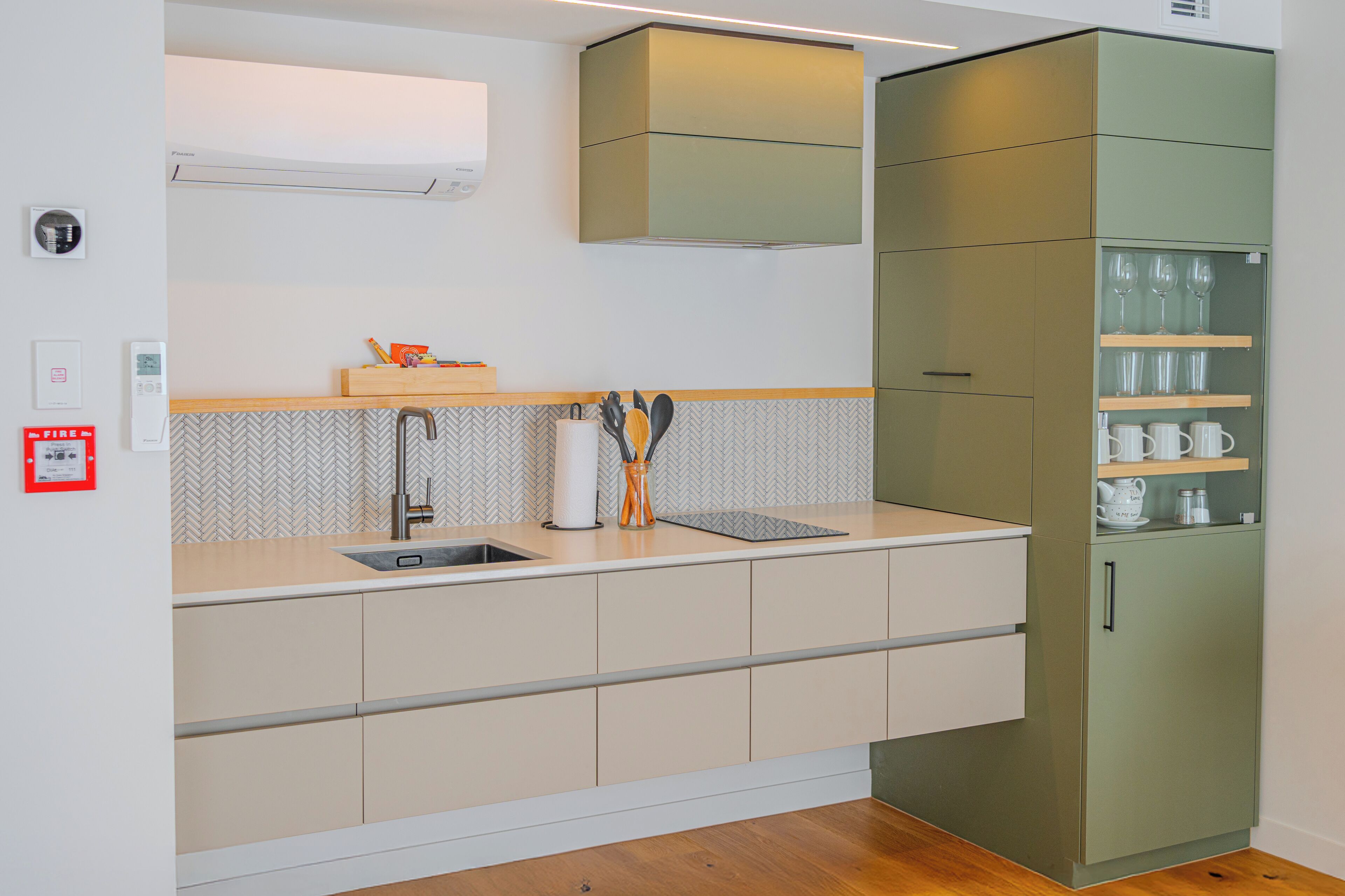 Eine moderne Küche mit integriertem Spülbecken, einer backsplash mit Zickzackmuster und einem grünen Schrank mit Regalen.