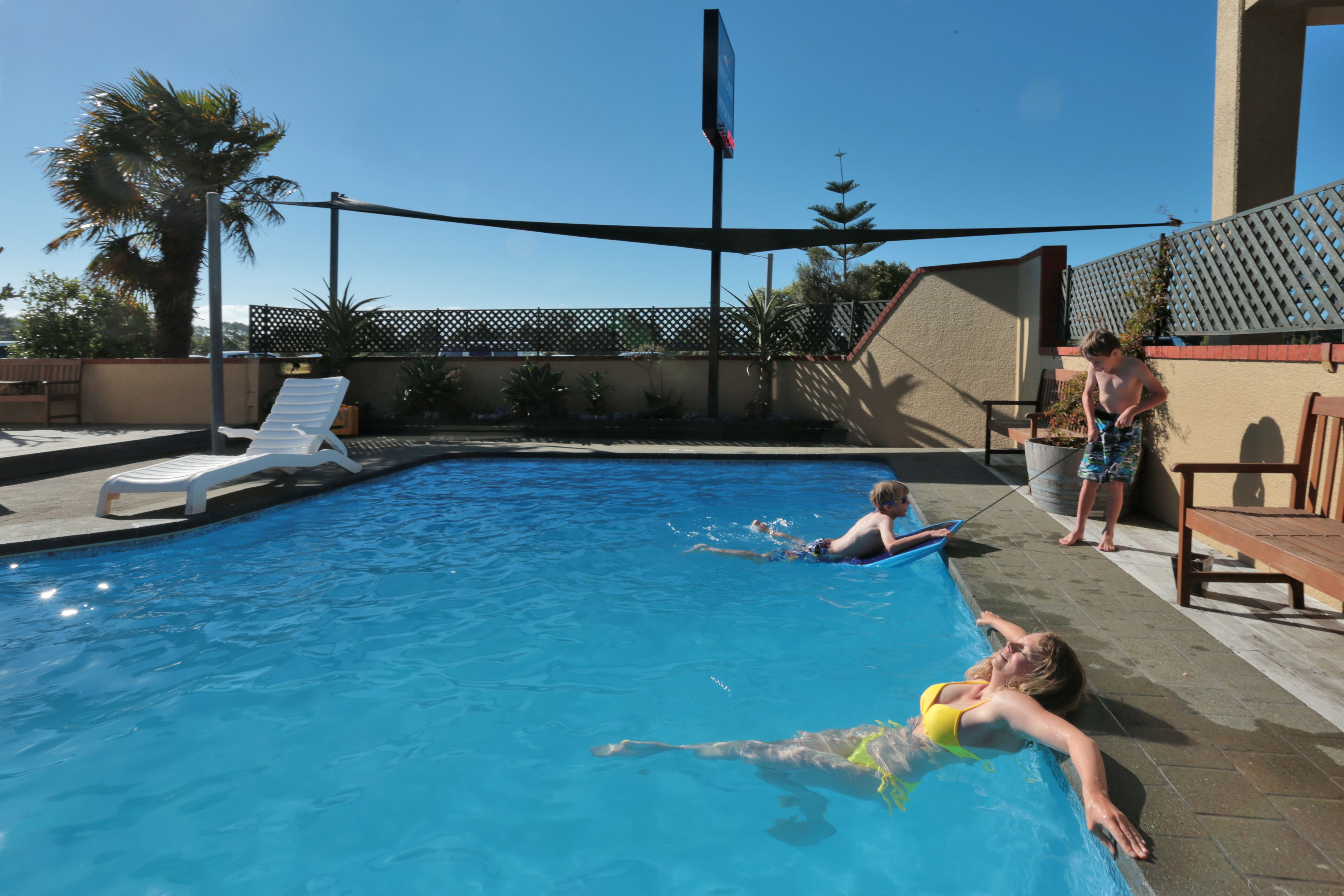 A swimming pool with lounge chairs and a wooden deck.