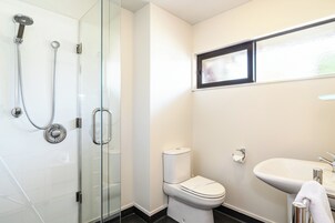 A bathroom with a glass-enclosed shower, a toilet, and a sink.