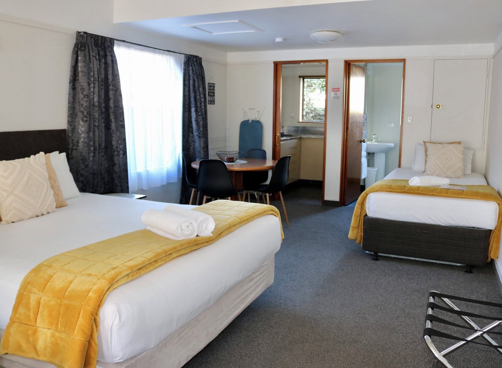 A hotel room with two beds, a desk, and a bathroom.