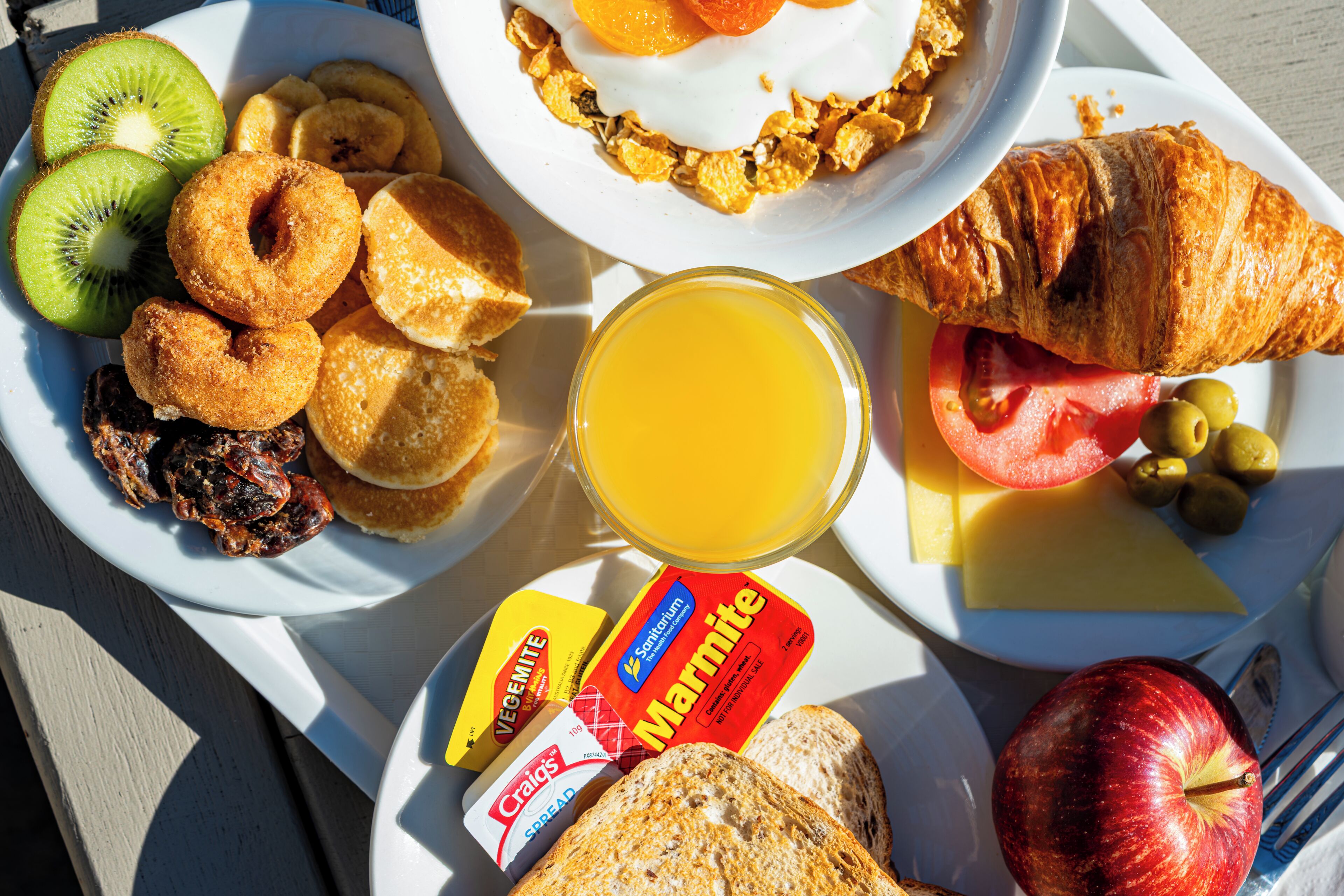 Ein Frühstückswagen mit verschiedenen Speisen, darunter Toast, Obst und ein Croissant.