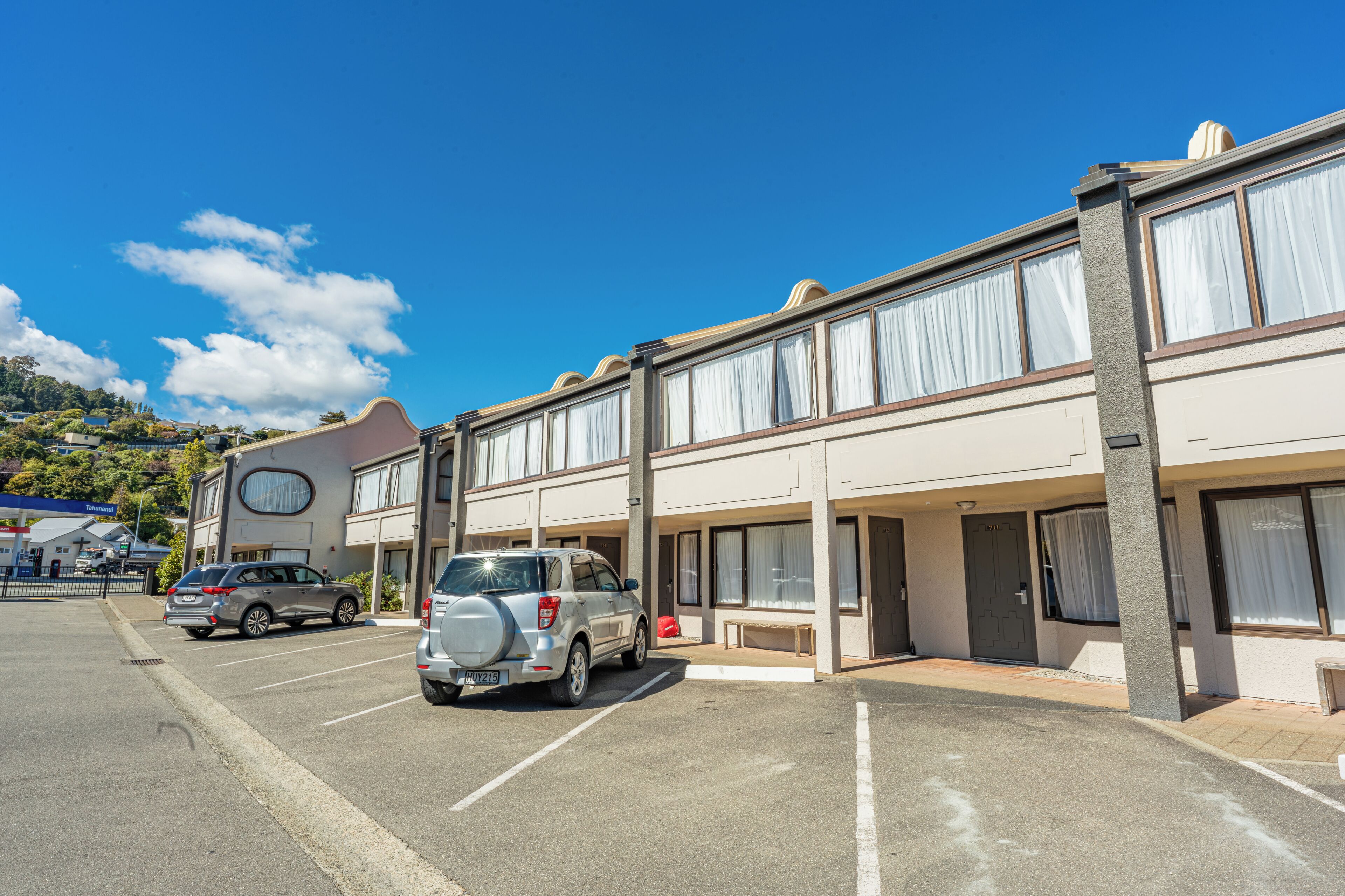 A hotel with a parking lot, a building with large windows, and a car parked in the lot.