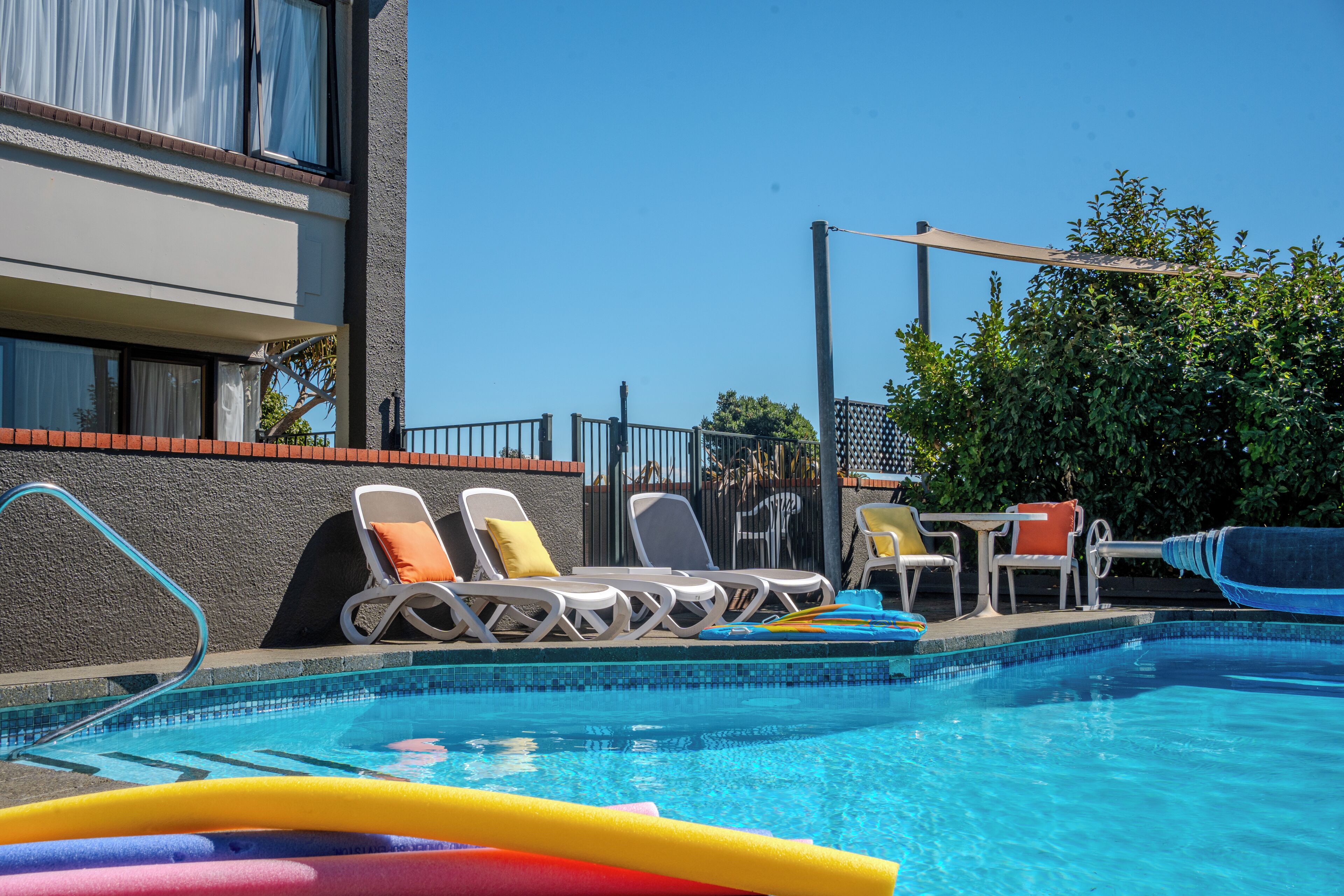 A swimming pool with lounge chairs and a covered area.