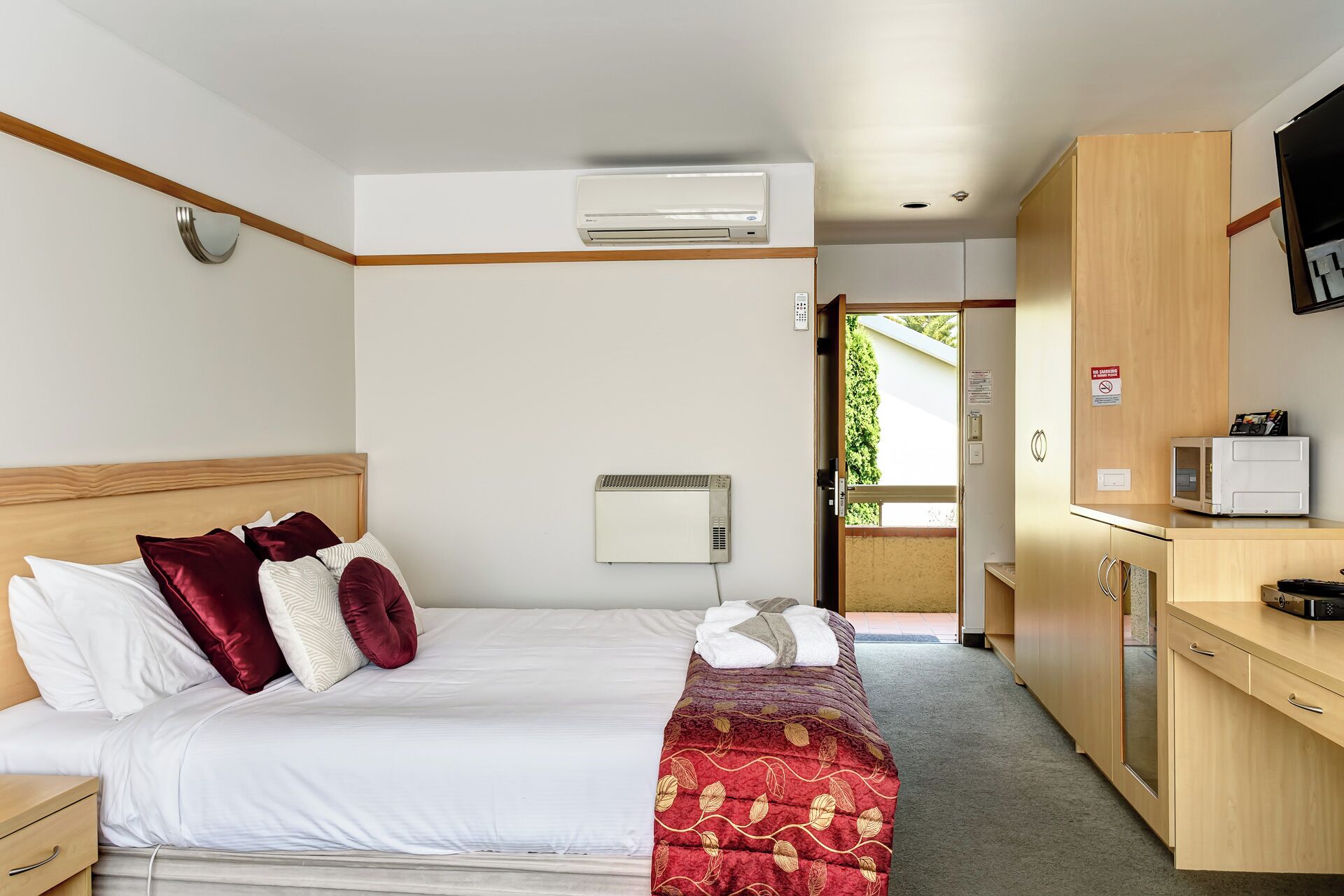 Ein Hotelzimmer mit Bett, Schreibtisch, Klimaanlage und Blick ins Freie.