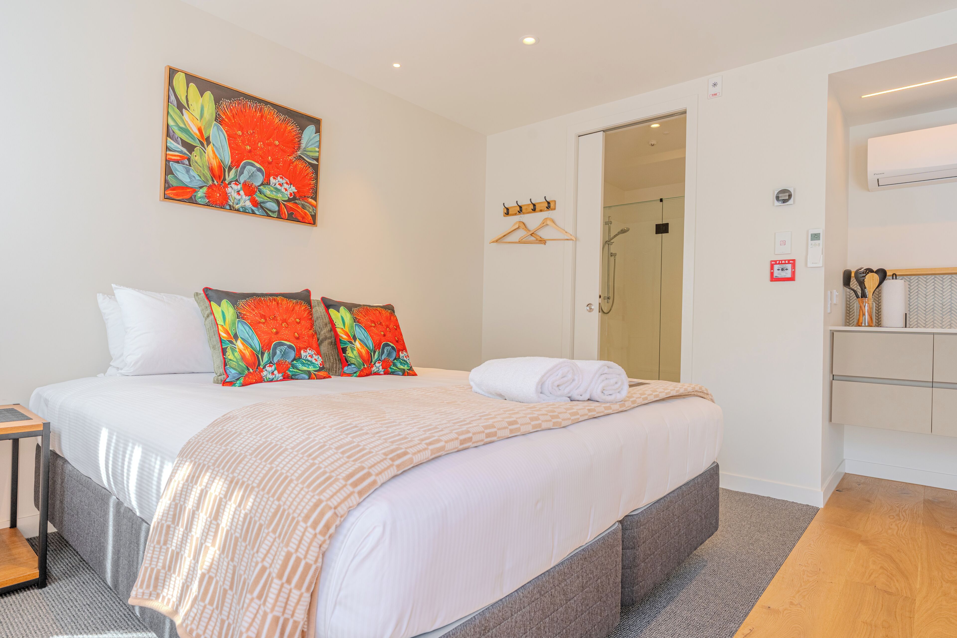 Habitació d'hotel amb llit, un quadre, dutxa i bany amb penjador de tovalloles.