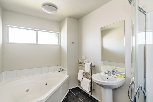 Un baño moderno con bañera, lavamanos y un espejo grande.