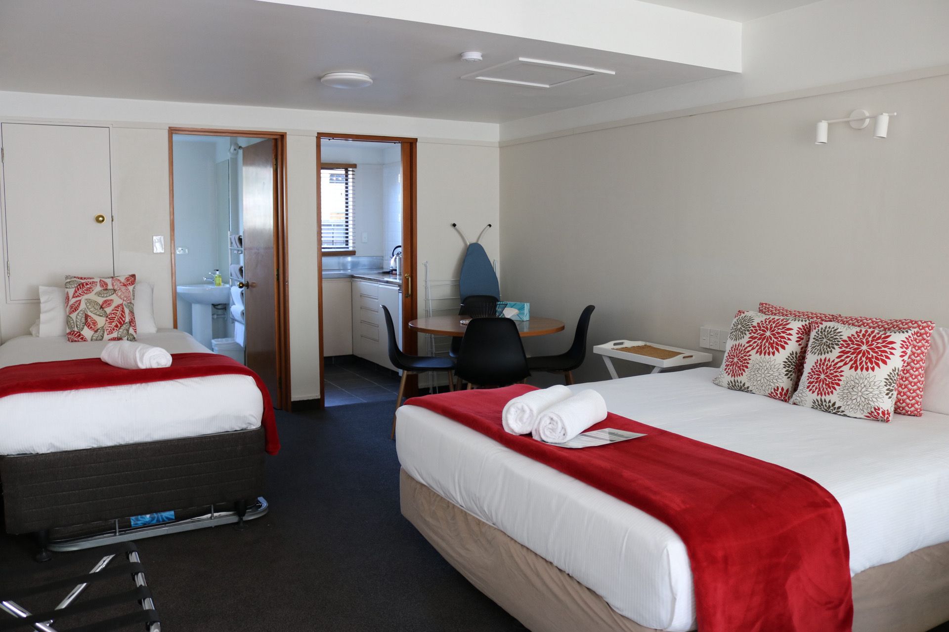 A hotel room with two beds, a desk, and a bathroom.