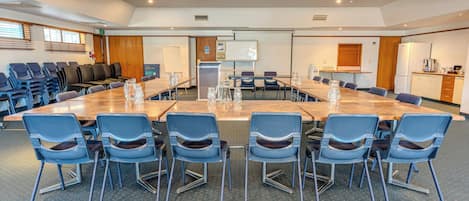 A conference room with a long table, chairs, a whiteboard, and a kitchenette.