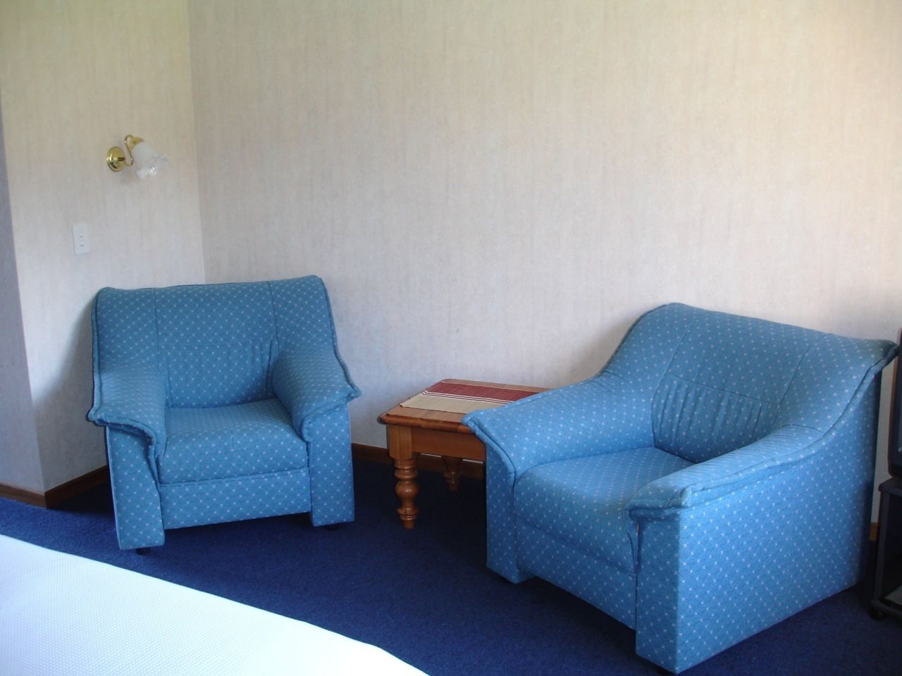 A room with two blue armchairs and a small wooden table.