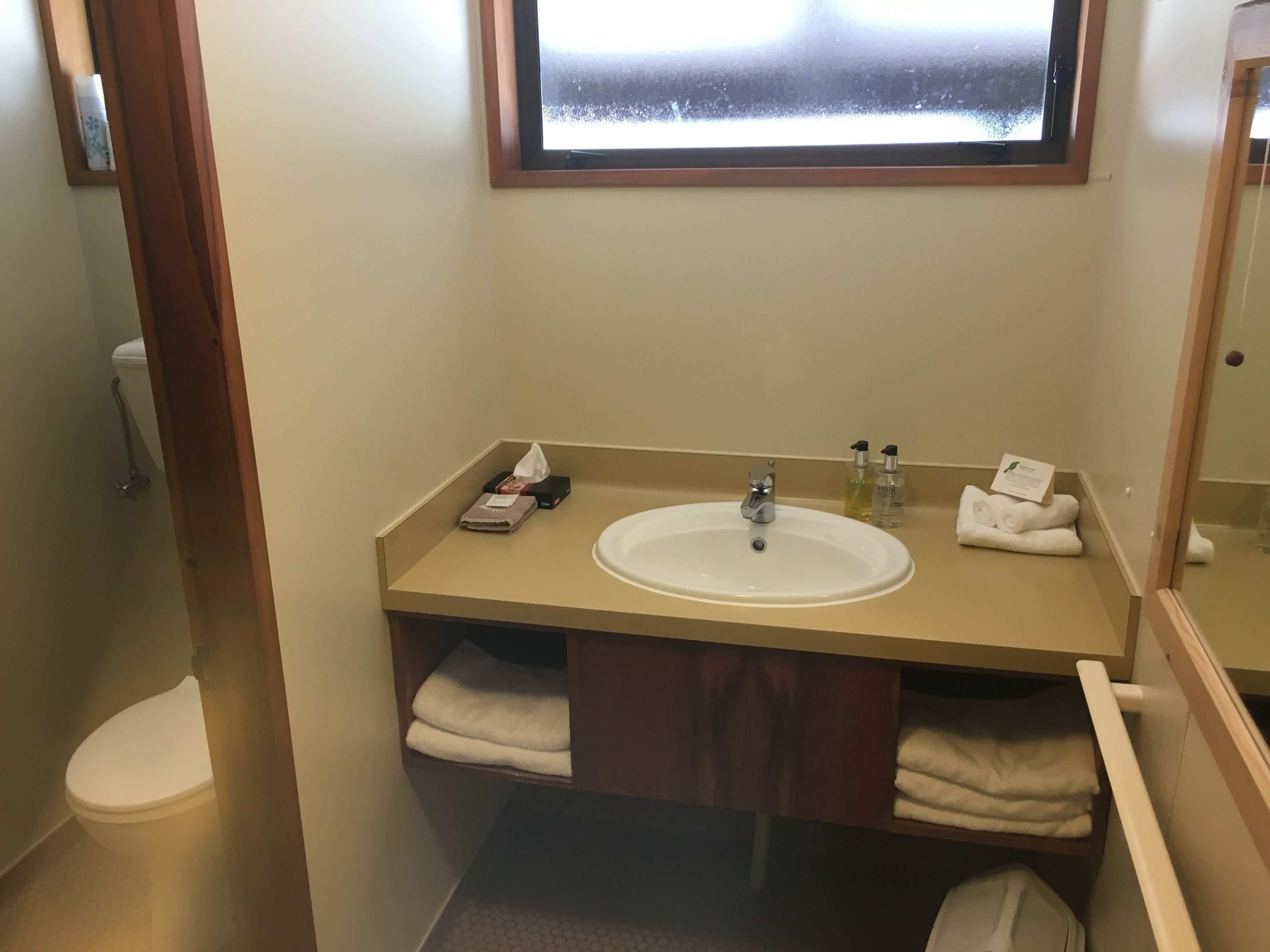 Un baño con lavabo, espejo y perchero para toallas.