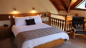 Un dormitorio con cama de madera, una mesita de noche, una silla y vistas al exterior.
