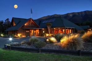 A lodge with a prominent mountain backdrop, a large entrance, and solar panels on the roof.