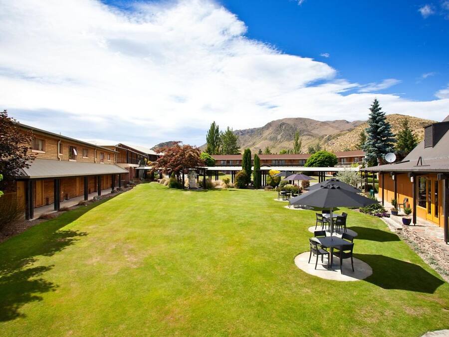 A courtyard with a lawn, outdoor seating, and buildings with large windows.