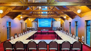 A conference room with a long table, chairs, a projector screen, and a red carpet. - Distinction Heritage Gateway Hotel (Omarama)
