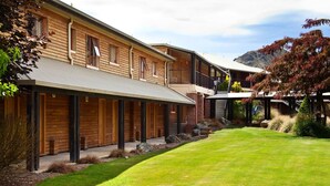 A two-story wooden building with a covered outdoor area and a well-maintained lawn. - Distinction Heritage Gateway Hotel (Omarama)