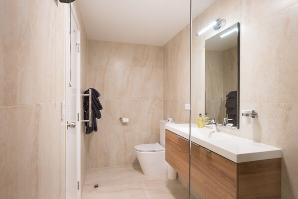 A modern bathroom with a shower, toilet, and vanity.