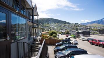 A hotel with a view of a parking lot and a mountainous landscape.