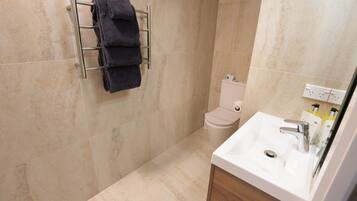 A bathroom with a toilet, sink, and towel rack.