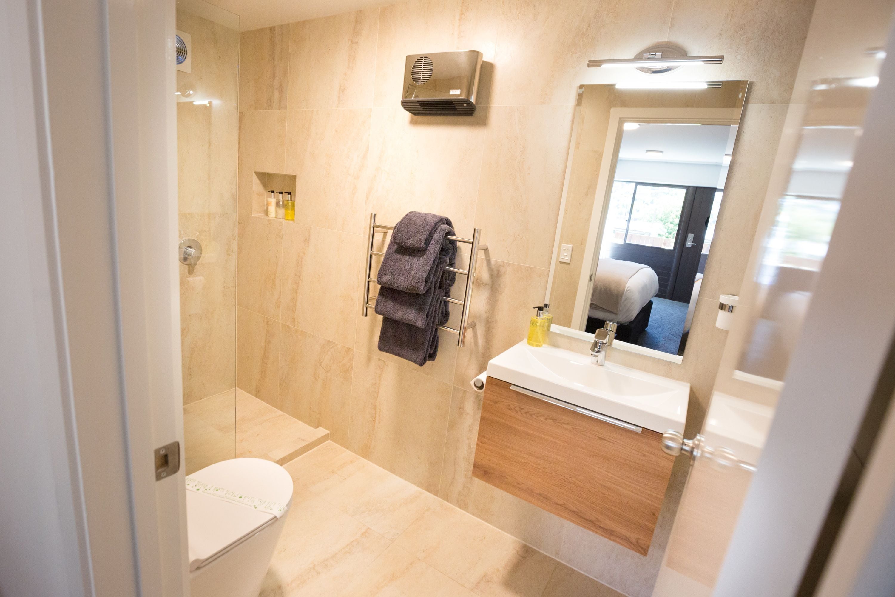 A modern bathroom with a shower, toilet, sink, and towel rack.