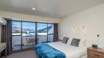 Un dormitorio con una cama grande, un escritorio y vistas a las montañas a través de una puerta corredera.