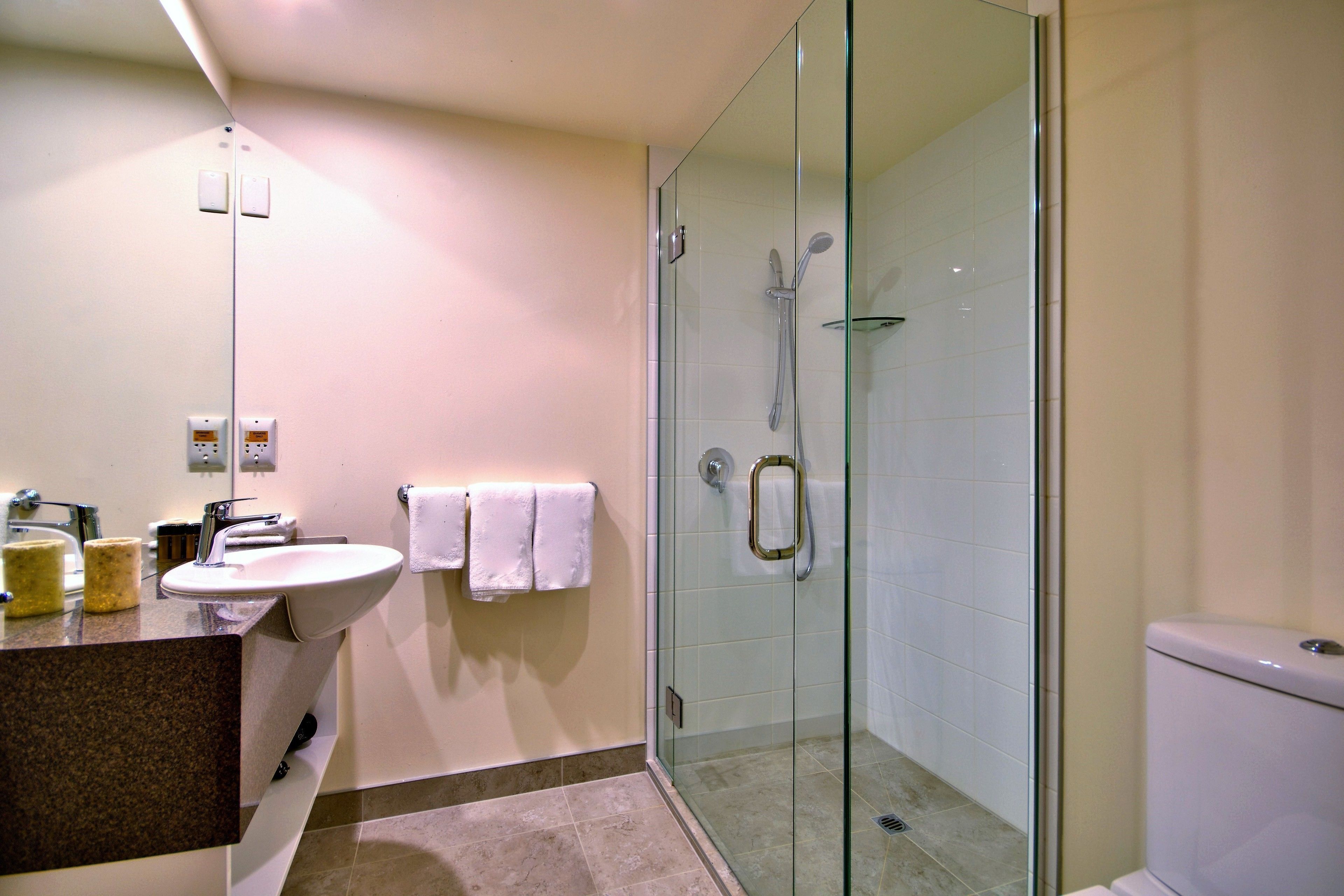 A modern bathroom with a glass-enclosed shower, a sink, and a toilet.