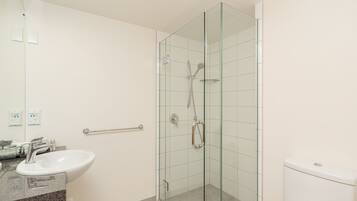 A bathroom with a glass-enclosed shower, a sink, and a toilet.