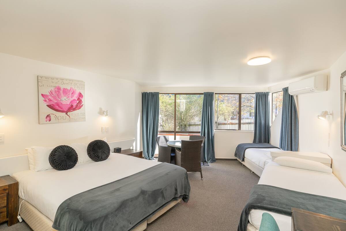 A hotel room with two beds, a dining table, and a chair.