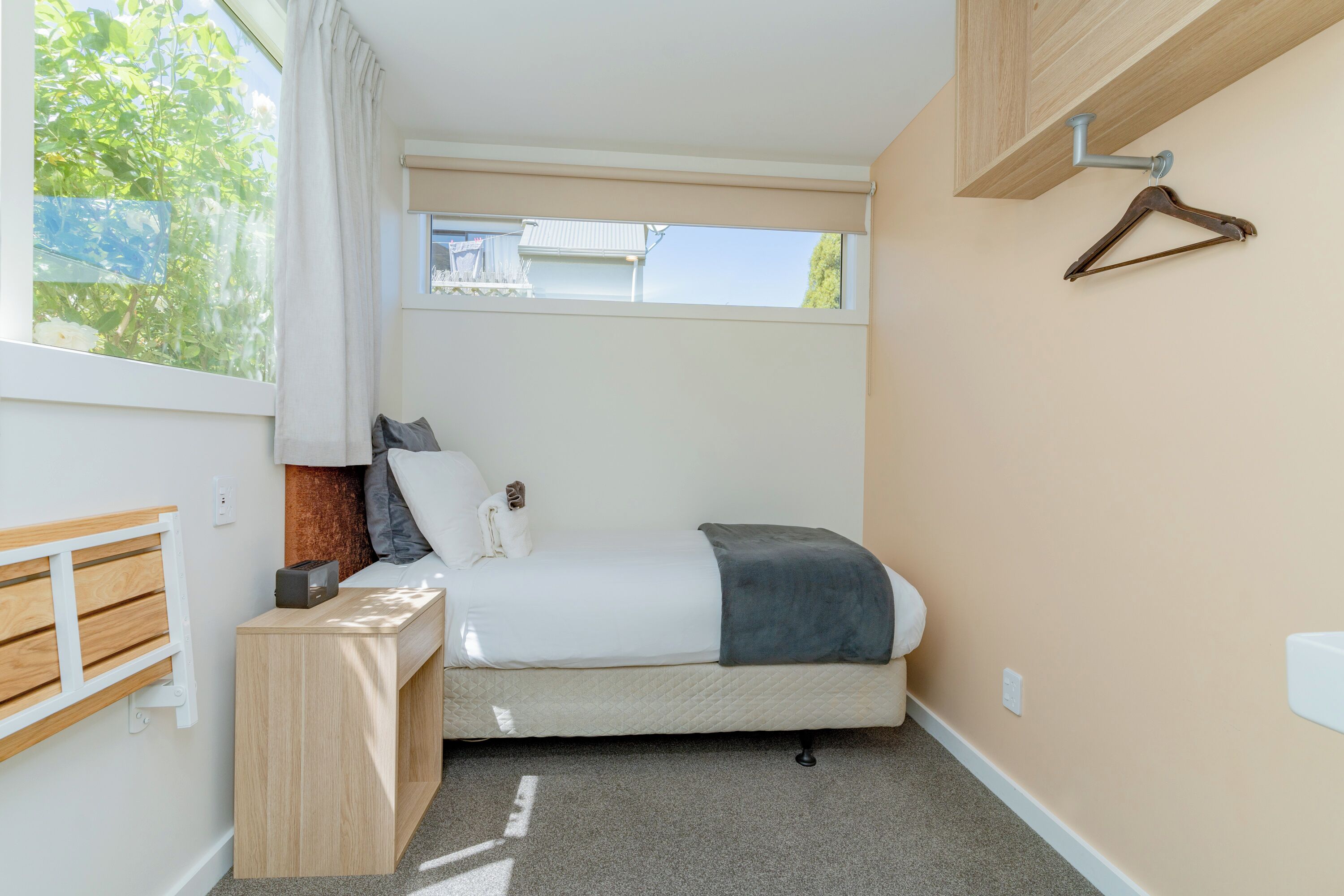 A compact bedroom with a bed, bedside table, and a window with curtains.