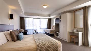 A hotel room with a large bed, a desk, a wardrobe, and a television.